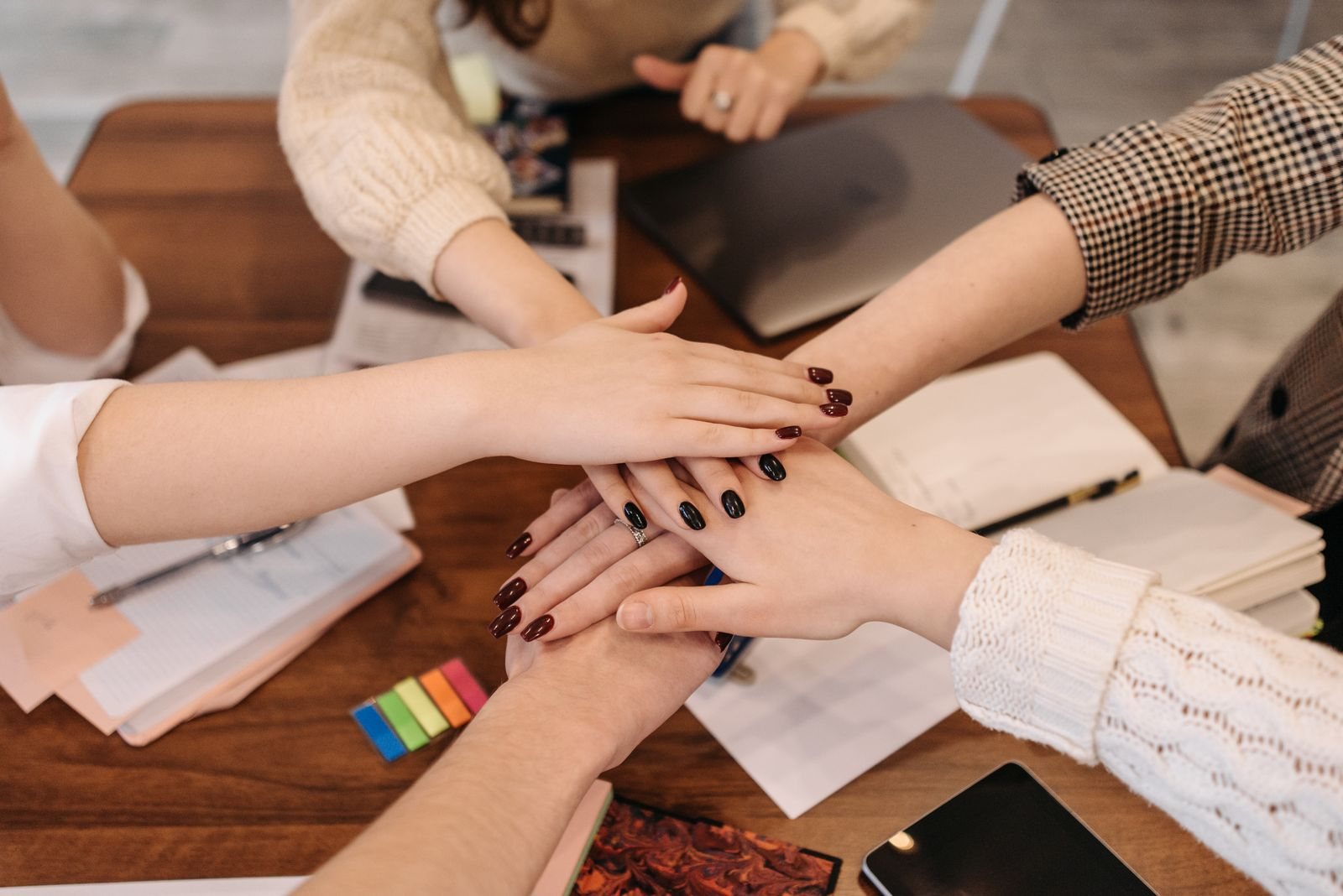 Équipe réunissant ses mains autour d'un bureau, en signe de collaboration